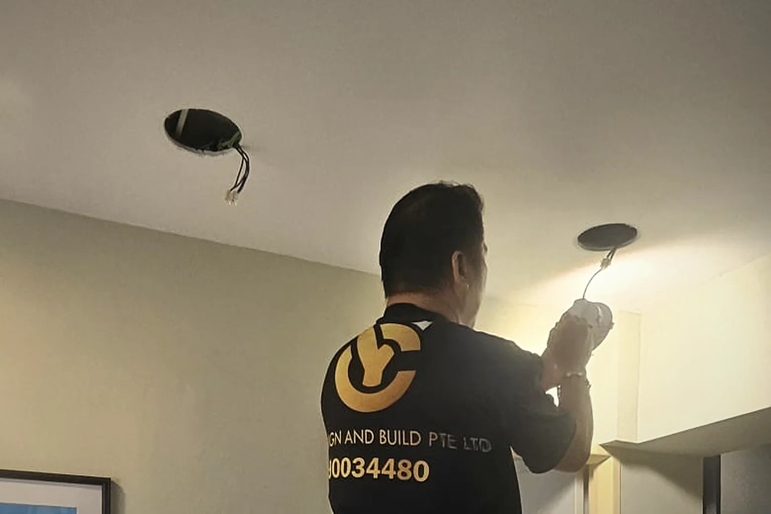 A YC electrician fitting a ceiling light