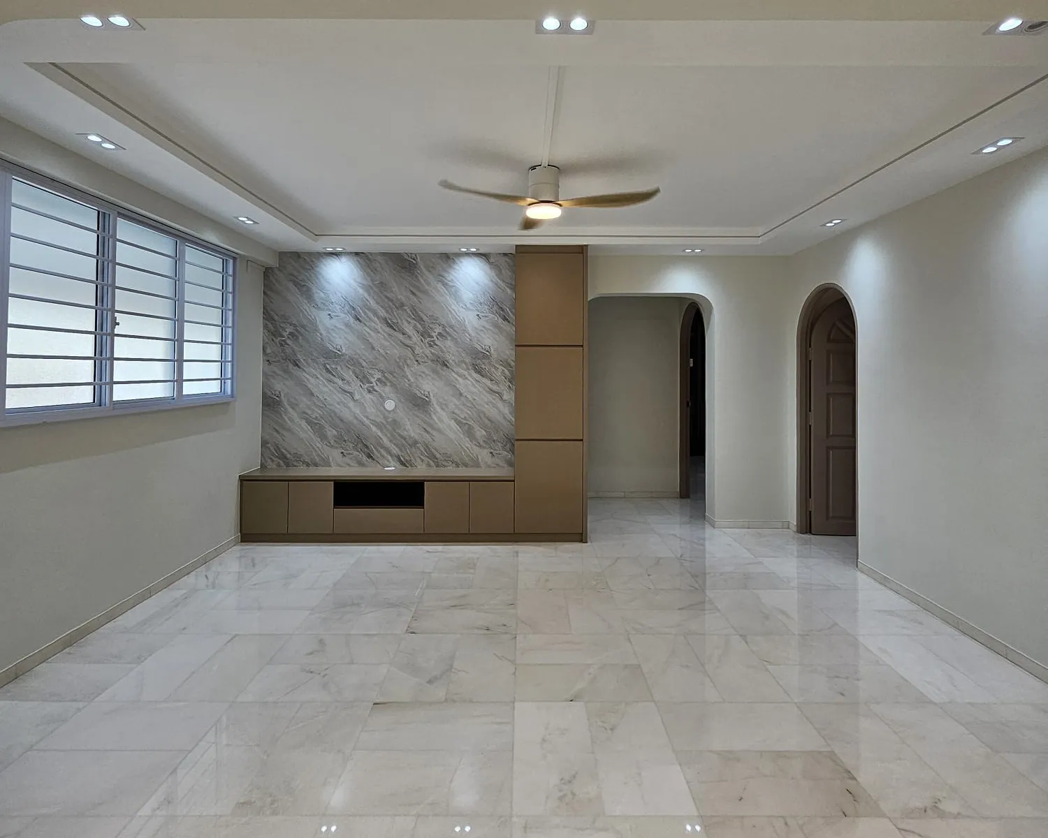 A finished living room with marble-look floor tiles, a stone-look feature wall and an archway